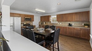 Una cocina moderna con armarios de madera, una isla central y un comedor con sillas.