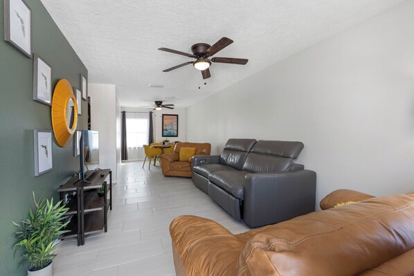 A living room with a sofa, a coffee table, and a ceiling fan.