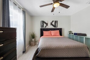 A bedroom with a bed, a ceiling fan, a nightstand with a plant, and a wall-mounted shelf. - Art Haus-Stunning Apt nr arprt and beaches Slps 6! (Tampa)