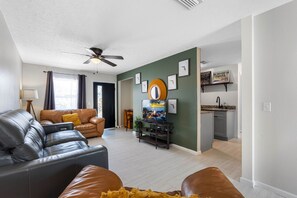 A living room with a sofa, TV, and a ceiling fan. - Art Haus-Stunning Apt nr arprt and beaches Slps 6! (Tampa)
