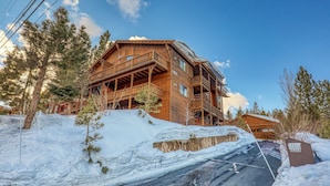 Eine Holzhütte mit Balkon, umgeben von Schnee und Bäumen.
