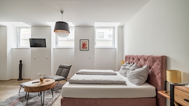 A modern bedroom with a large bed, a desk, and a chair. There are two windows providing natural light. - Prime Loft, Prime Loft near Naschmarkt (Vienna)