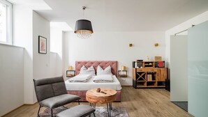 A modern bedroom with a large bed, a grey armchair, a small wooden table, and a pendant light. - Prime Loft, Prime Loft near Naschmarkt (Vienna)