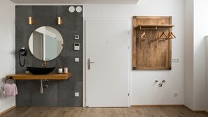 A modern bathroom with a wooden vanity, a round mirror, and a wooden coat rack. - Prime Loft, Prime Loft near Naschmarkt (Vienna)