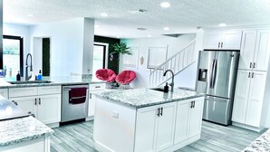 A modern kitchen with white cabinetry, a granite countertop, and a stainless steel refrigerator. - The American Dream🇺🇸Walk to Beach🌴Launch Views🚀 (Cocoa Beach)