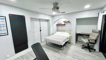 A bedroom with a bed, a desk, a chair, a wardrobe, and a ceiling fan.
