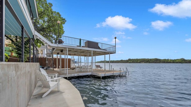 Een pand aan het water met een steiger die in het water uitsteekt, een overdekt terras en een gebouw naast het water.