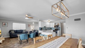 Een moderne woonkamer met een eethoek, keuken en plafondventilator.