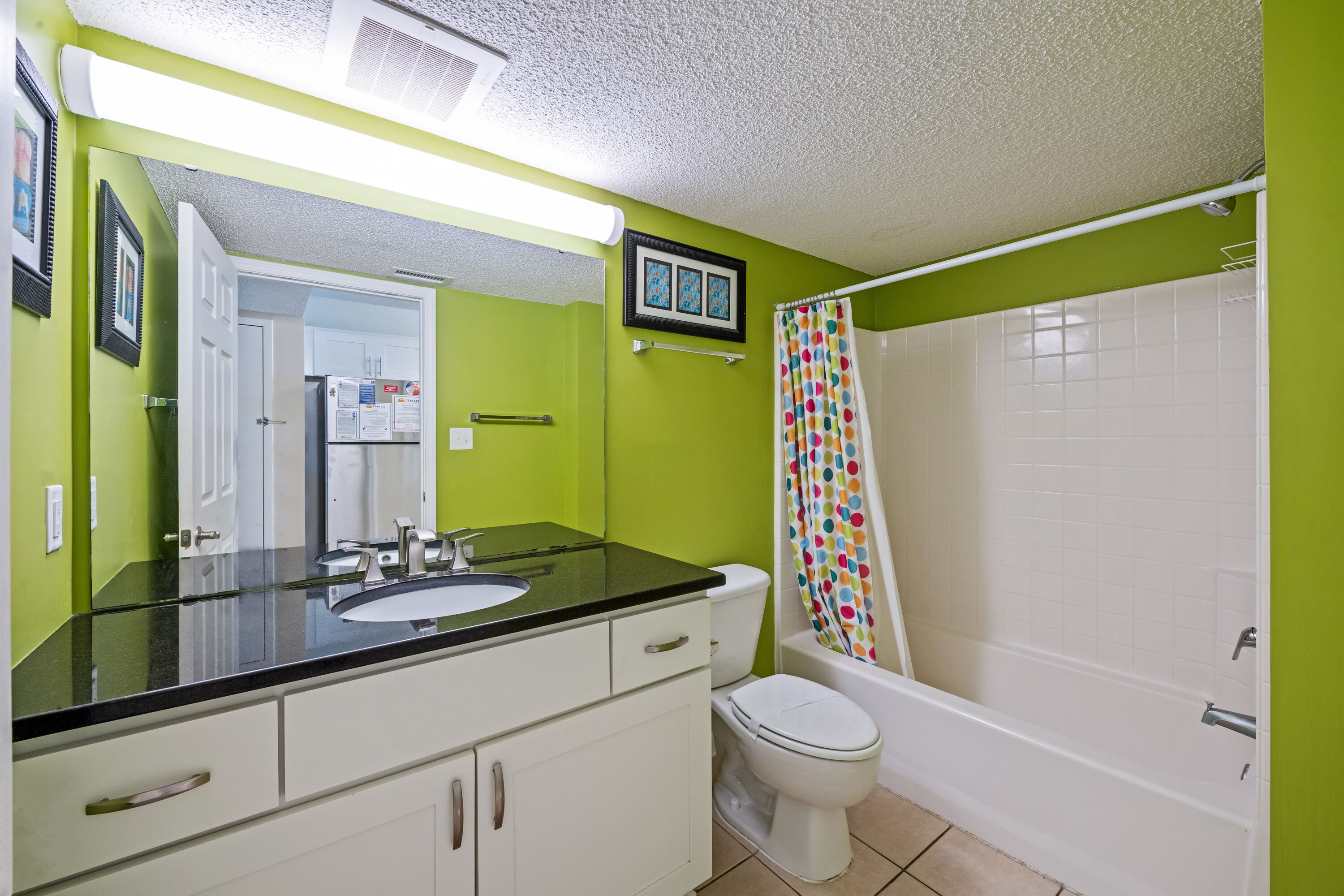 A bathroom with a green wall, white sink, and a white bathtub.