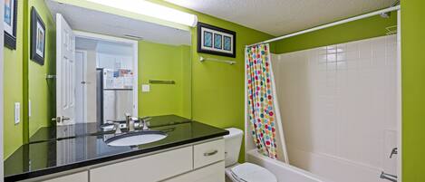 A bathroom with a green wall, white sink, and a white bathtub.