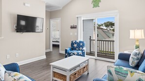 A living room with a flat-screen TV, a star-patterned armchair, a blue sofa, and a coffee table with baskets.