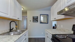 A kitchen with white cabinets, granite countertops, a black stove, and a stainless steel range hood. - 15 Mins to Closest Beach, 10 minutes from Downtown, with FIrepit! (Tampa)