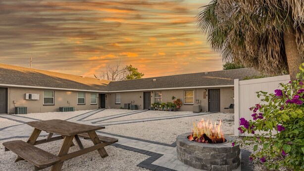 A courtyard with a fire pit and picnic table, surrounded by buildings with a gravel path. - 15 Mins to Closest Beach, 10 minutes from Downtown, with FIrepit! (Tampa)