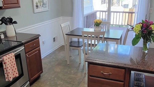 A kitchen with a dining area, a wooden cabinet, a countertop, and a window with curtains.