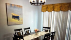 A dining area with a table and chairs, a painting on the wall, and a window with vertical blinds. - Beautiful home in Oldsmar (Oldsmar)