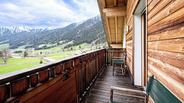 Un balcon en bois offrant une vue sur un paysage montagneux.