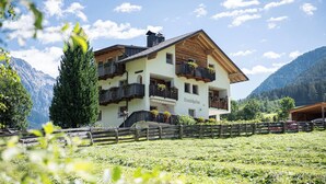 Un immeuble à plusieurs étages doté de balcons, d’une clôture en bois et ayant une chaîne de montagnes en arrière-plan.