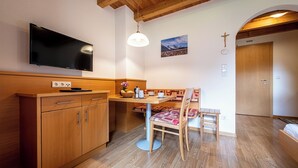 Une cuisine moderne avec des meubles en bois, un téléviseur encastré et un coin repas comprenant une banquette et des chaises.