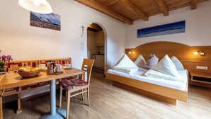 Une pièce chaleureuse avec un plafond en bois, un lit avec des oreillers, une table à manger avec des chaises et un luminaire fixé au mur.