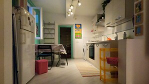 A compact kitchen with a dining area, a washing machine, and a small table with chairs.