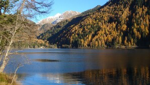 Un lago tranquilo rodeado de árboles y montañas de colores otoñales.