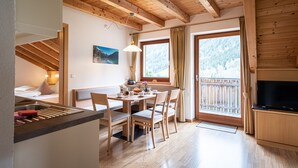 Interior acogedor de una cabaña con comedor, vigas de madera, televisor y una vista panorámica a través de las ventanas.
