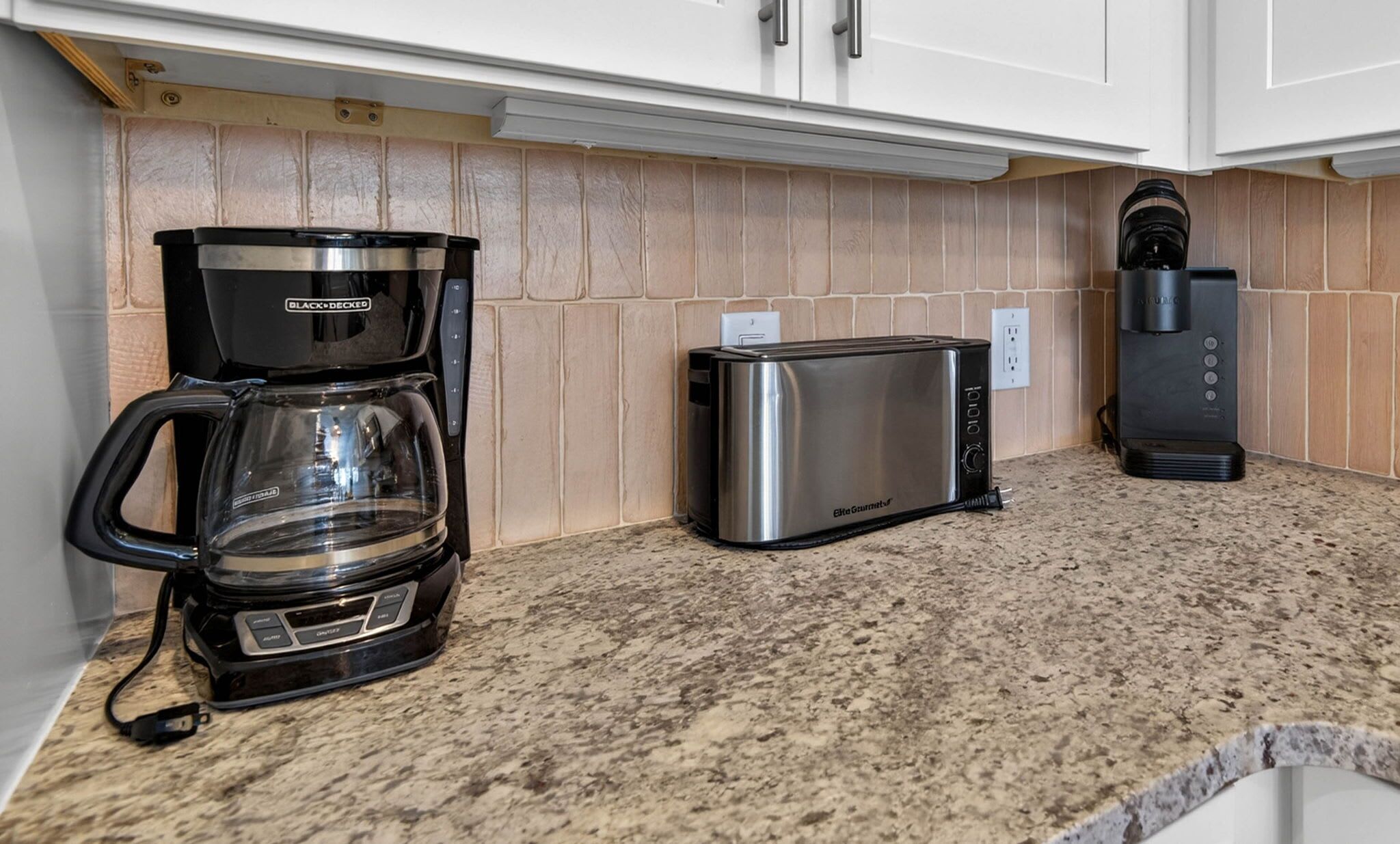 A kitchen with a coffee maker, toaster, and electric kettle.