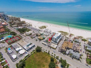 An aerial view of a coastal city with a beach, buildings, and a construction site.