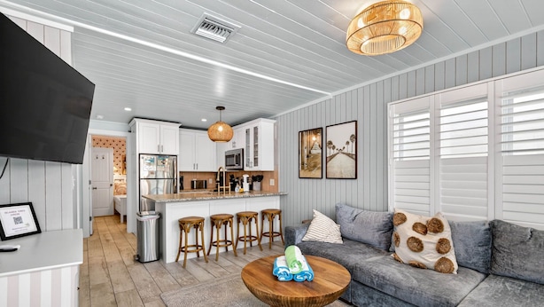 A modern kitchen with white cabinets, a central island, and bar stools. - Island Vibes House Steps from Clearwater Beach (Clearwater Beach)