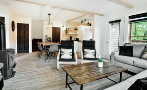 A modern living room with a fireplace, a dining area, and a kitchen.