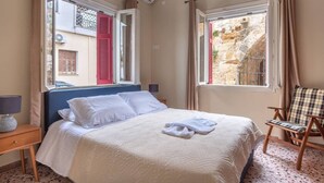 A bedroom with a bed, a chair, and a window with curtains. - 4 Guests - Veneris Residence Apartment in Chania (Chania)