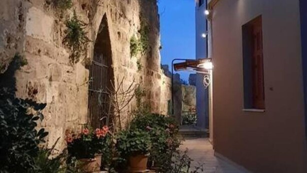 A narrow alleyway with a stone wall on one side and a building on the other. There are potted plants in the foreground. - 4 Guests - Veneris Residence Apartment in Chania (Chania)
