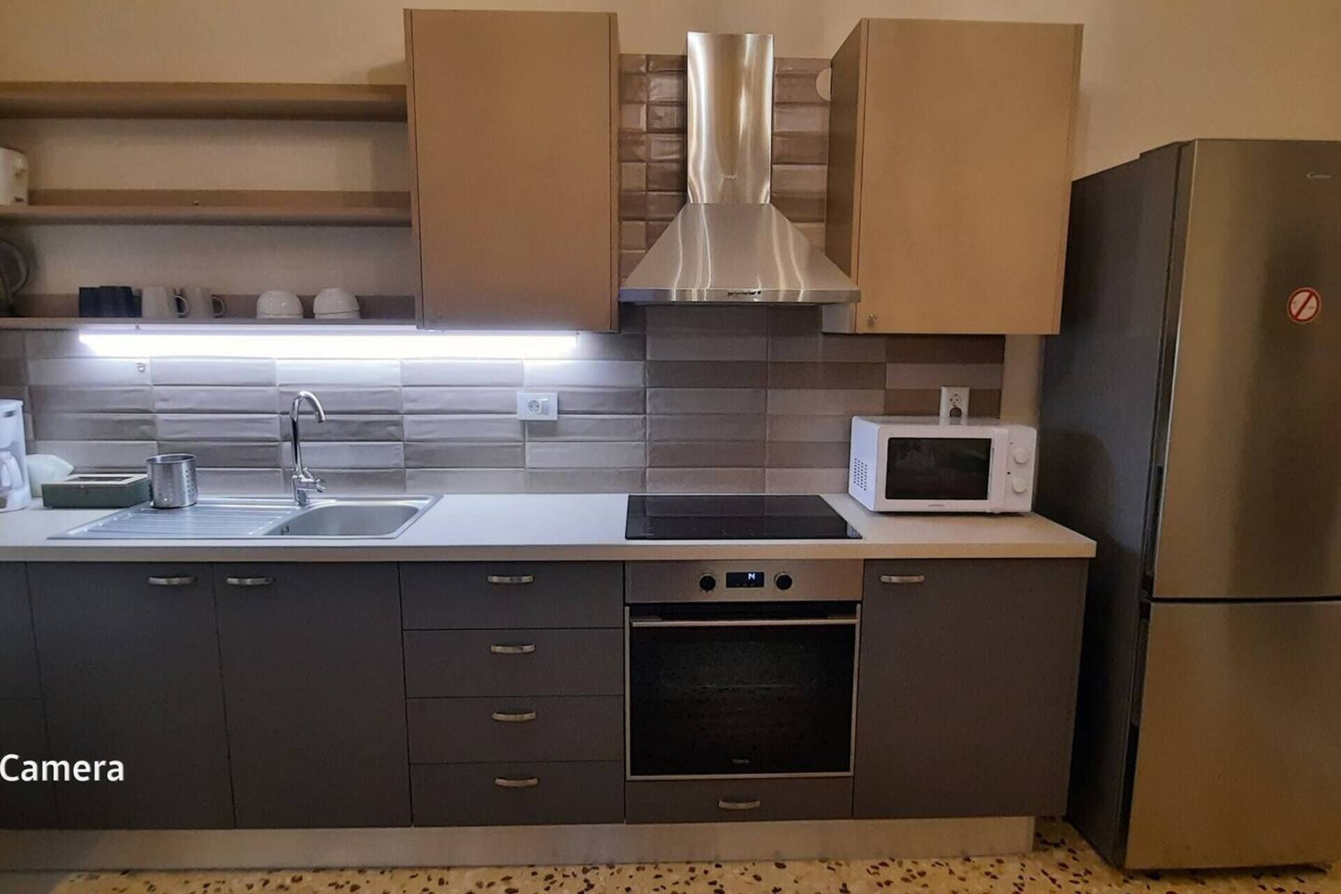 A modern kitchen with a stainless steel range hood, a microwave, and a built-in oven.