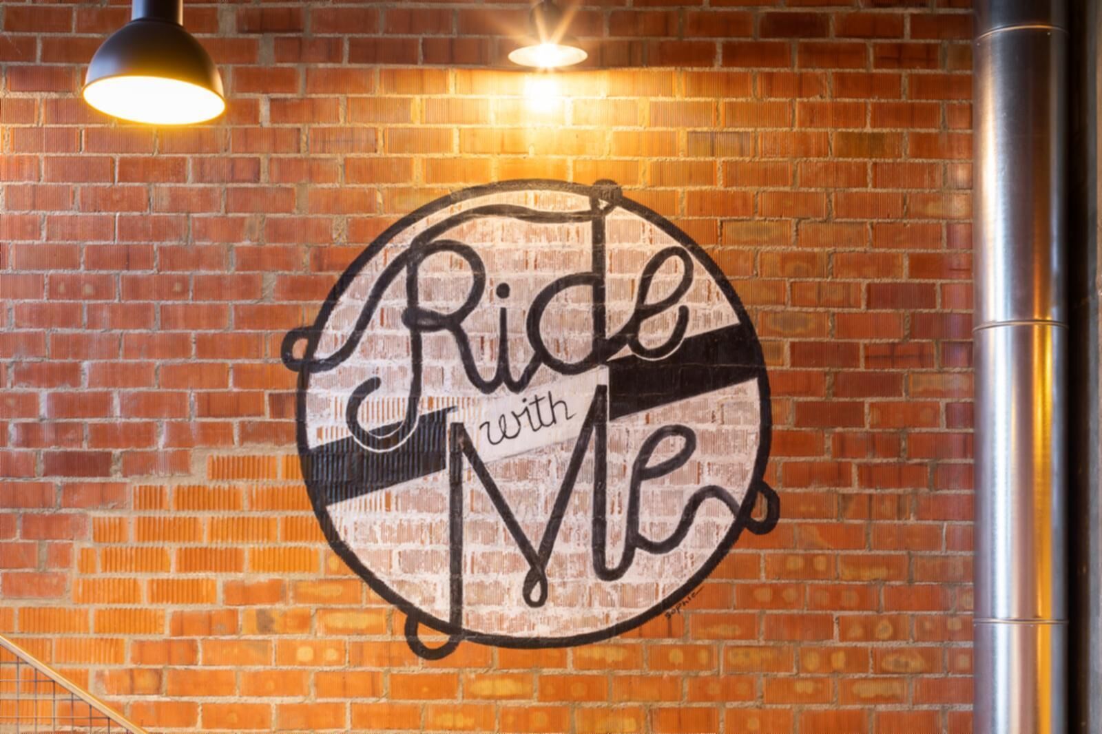 Una pared con un letrero circular que dice 'Ride with Me'.