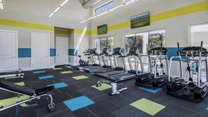 Un gimnasio con cintas de correr, bicicletas estáticas y una máquina de remo.