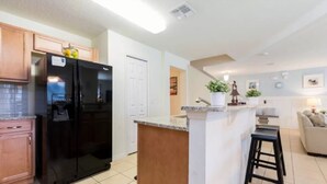 Una cocina moderna con un refrigerador negro, armarios de madera y una pequeña isla con taburetes.