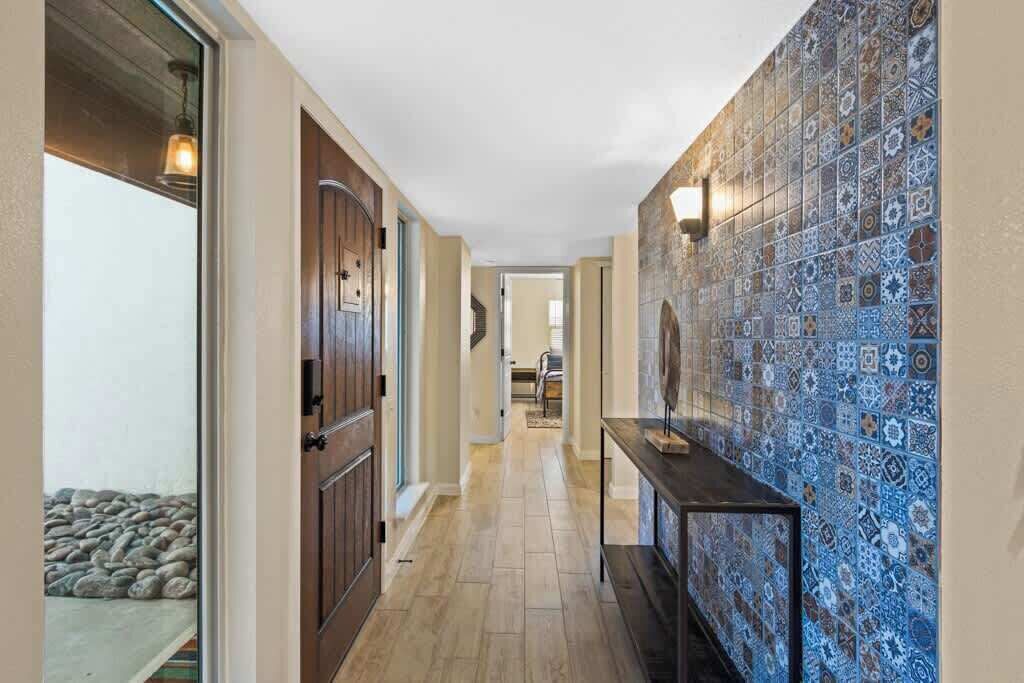 A hallway with patterned tiles, a wooden door, and a small table.