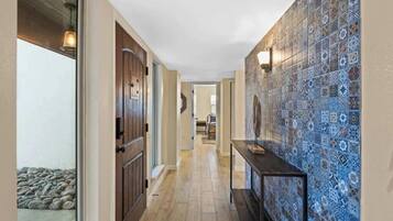 A hallway with patterned tiles, a wooden door, and a small table.