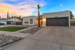 A modern residential property with a garage, a well-maintained lawn, and a palm tree. - Eastside Spanish Castilla (El Paso)