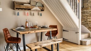 A dining area with a wooden table, two chairs, a bench, and a hanging light fixture. - Old Stable Cottage, Kingham, Chipping Norton (Kingham)