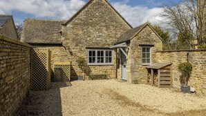 A stone building with a triangular roof, a wooden bench, and a small shed. - Old Stable Cottage, Kingham, Chipping Norton (Kingham)