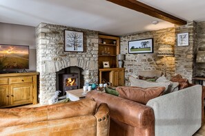 A stone fireplace, a television, a sofa, and a bookshelf in a cozy living room.