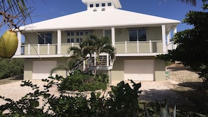 A two-story house with a white roof, multiple windows, and a covered front porch. - Private Home on Amazing Beach! 22 Steps to Beach!  (Coconut Bay)