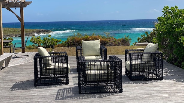 A wooden deck with outdoor furniture overlooking a coastal view. - Private Home on Amazing Beach! 22 Steps to Beach!  (Coconut Bay)