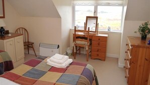 A bedroom with a bed, a desk, a chair, a dresser, and a radiator. - Airie Farmhouse -  a house that sleeps 6 guests  in 3 bedrooms (Castle Douglas)