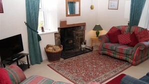 A living room with a fireplace, a television, and two sofas. - Airie Farmhouse -  a house that sleeps 6 guests  in 3 bedrooms (Castle Douglas)