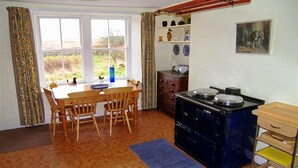 A compact kitchen with a dining table and chairs, a stove, and a small cabinet. - Airie Farmhouse -  a house that sleeps 6 guests  in 3 bedrooms (Castle Douglas)