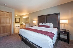 Relax in this inviting space with a large bed, bedside tables, and a door leading to a bathroom with a mirror and sink.