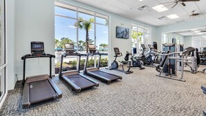 Une salle de sport équipée de tapis de course, de vélos d’exercice et d’appareils de musculation.