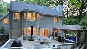 Une maison à deux étages dotée d’une terrasse, de mobilier d’extérieur et d’un jacuzzi.